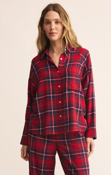 Woman wearing a red plaid pajama set against a beige background