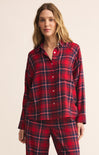 Woman wearing a red plaid pajama set against a beige background