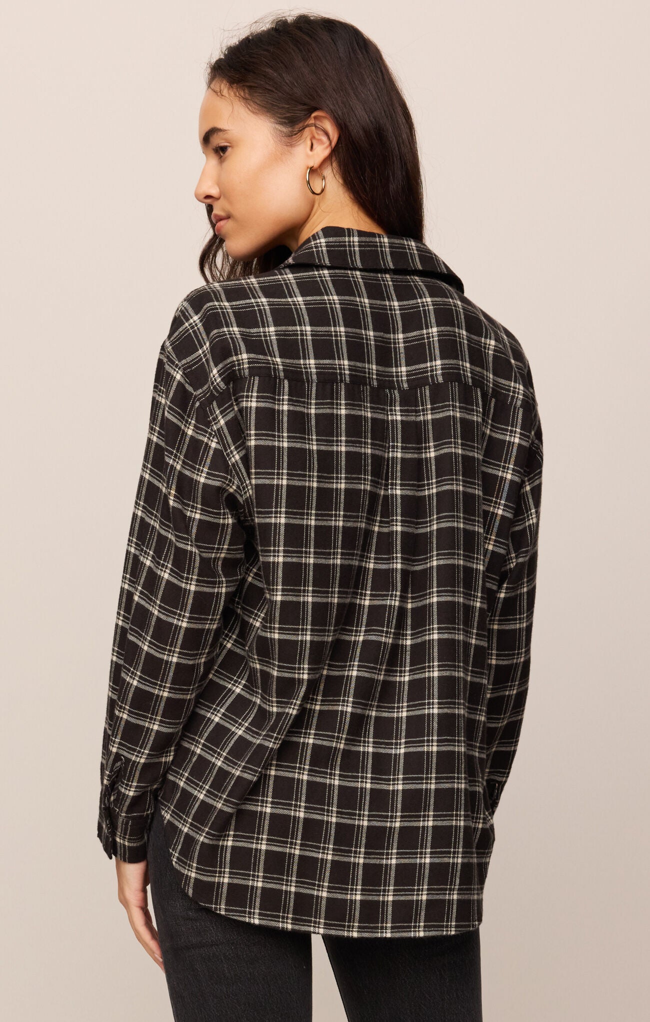 Woman wearing a black and white plaid shirt against a beige background