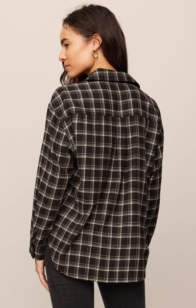 Woman wearing a black and white plaid shirt against a beige background