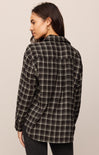 Woman wearing a black and white plaid shirt against a beige background