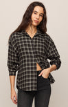 Woman wearing a plaid shirt and black pants against a plain background