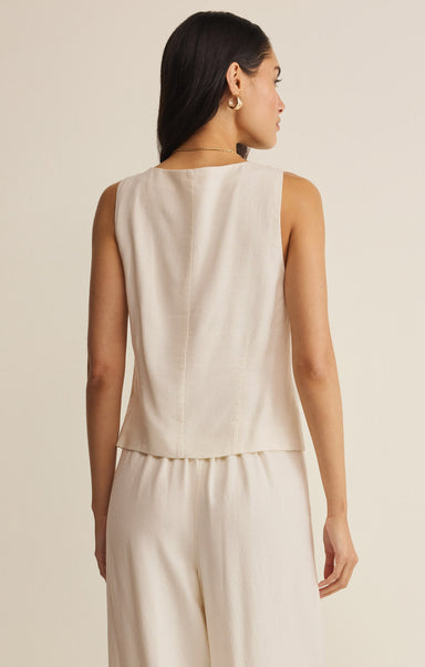 Woman wearing a beige sleeveless top and pants against a neutral background