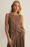 Woman wearing a brown sleeveless top and pants against a plain background