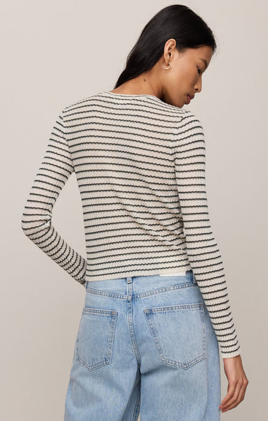 Woman wearing a striped sweater and jeans against a plain background