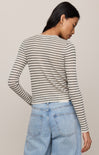 Woman wearing a striped sweater and jeans against a plain background