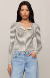 Woman wearing a striped long-sleeve top and blue jeans against a plain background