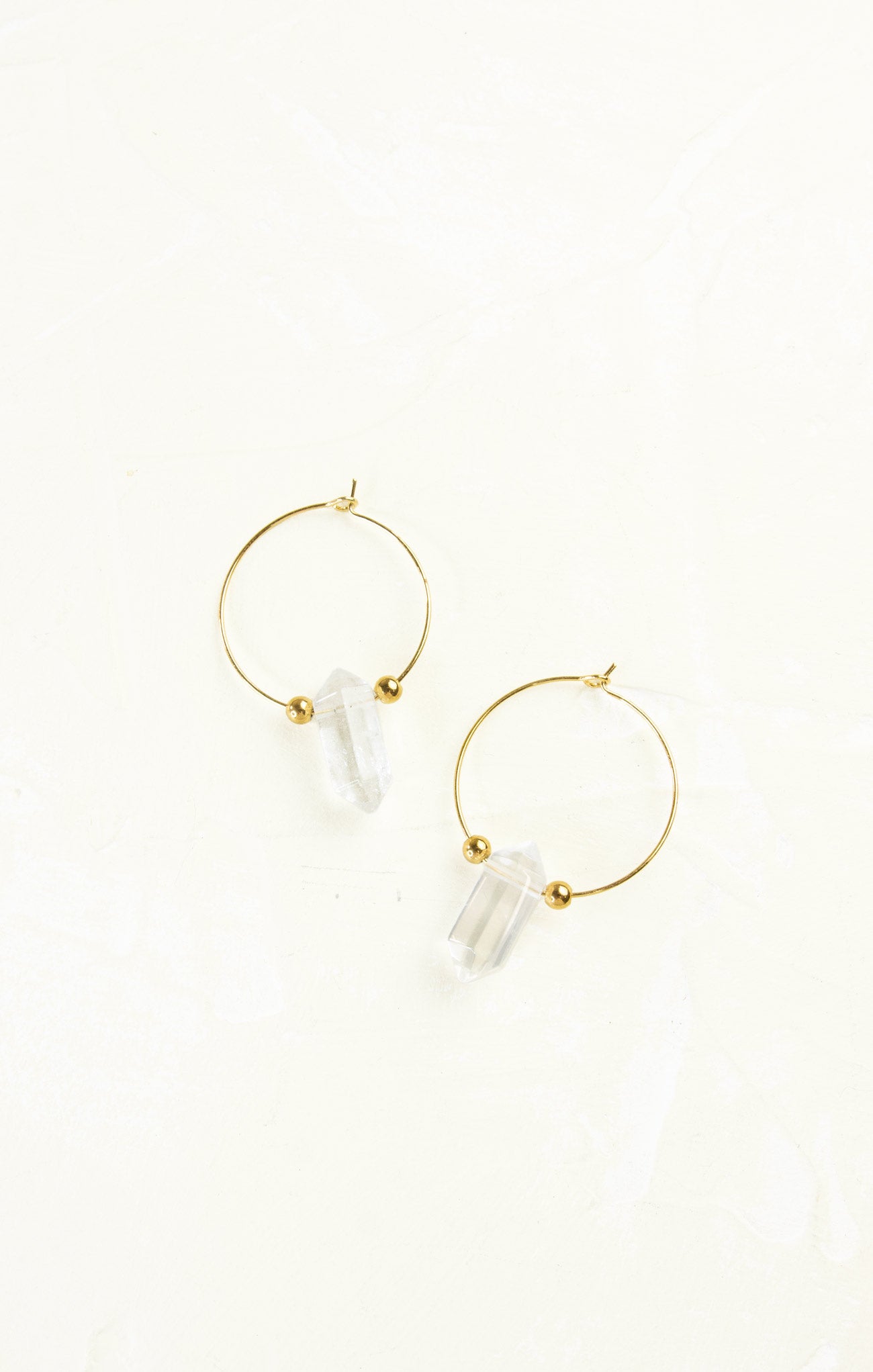 Gold hoop earrings with clear cylindrical beads on a white background