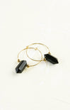 Gold hoop earrings with black geometric beads on a white background