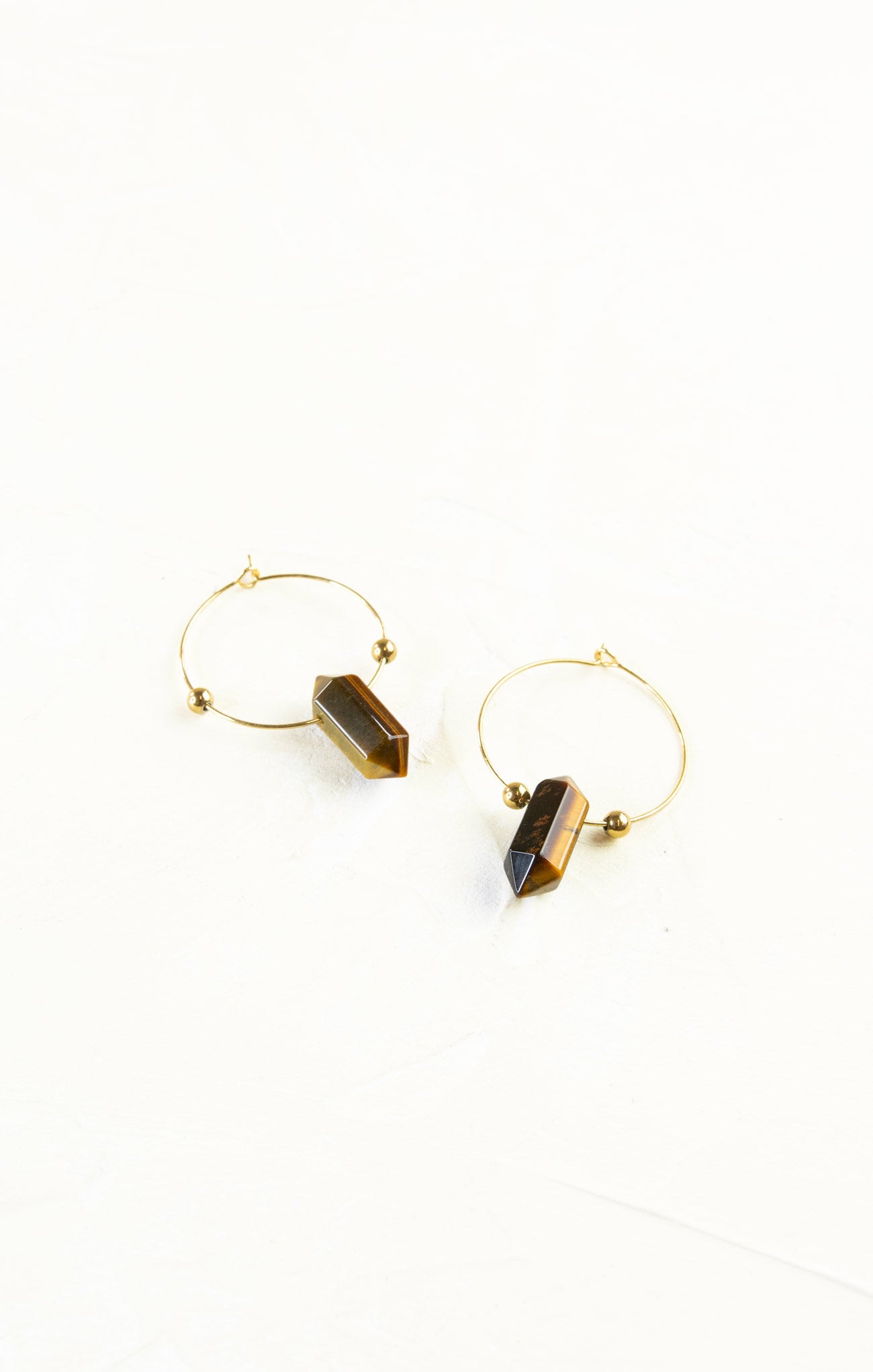 Gold hoop earrings with black stone accents on a white background