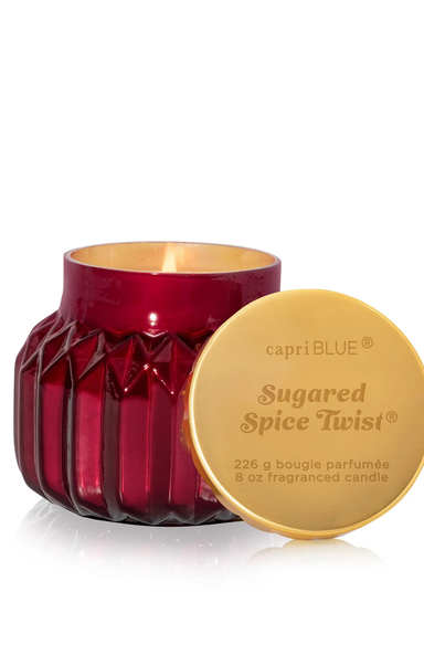 Red candle with gold lid labeled 'capri BLUE Sugared Spice Twist' on a white background