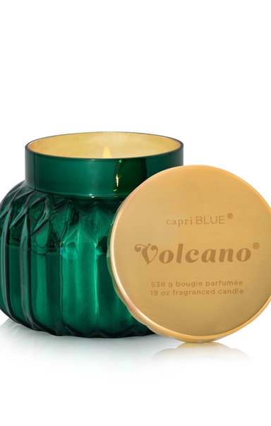 Green candle with gold lid labeled 'Volcano' by capri BLUE on a white background