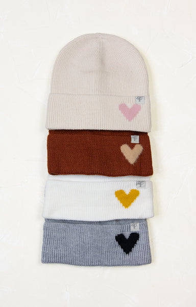 Stack of knit hats with heart designs on a white background