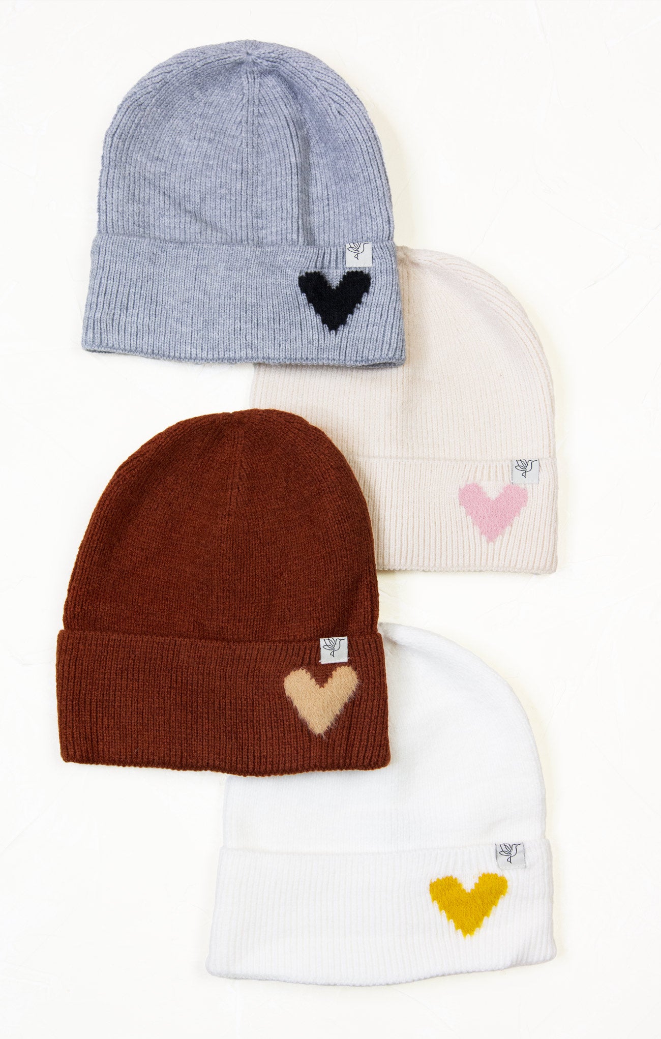 Four beanies with embroidered heart designs on a white background