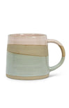 A handmade ceramic mug with a rustic, hand-rimmed finish, featuring horizontal bands of dusty pink, sandy beige, and pale sage green glaze, with a matching curved handle.