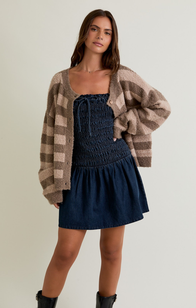 Woman wearing a blue dress and plaid cardigan on a plain background