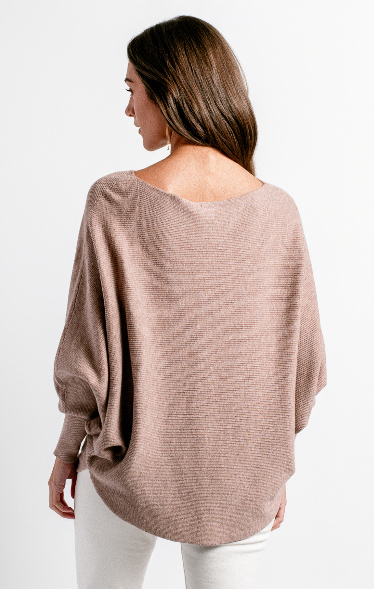 Woman wearing a beige sweater with a plain white background