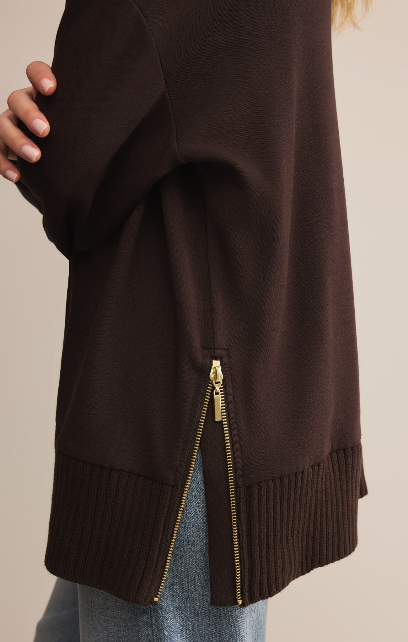 Brown jacket with a gold zipper on a neutral background