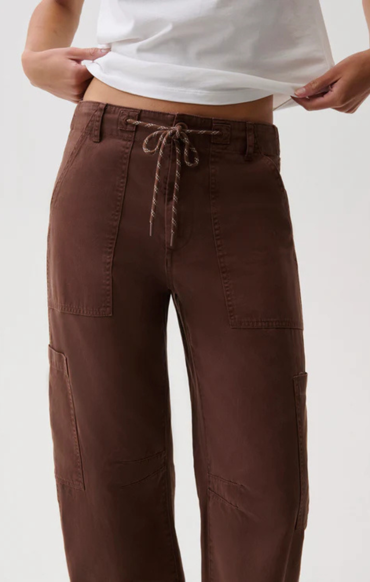 A person wearing brown wide-leg cargo pants with a drawstring waist, shown from the waist down against a plain light background.