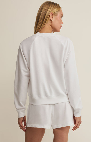 Woman wearing a white sweatshirt and shorts set against a beige background