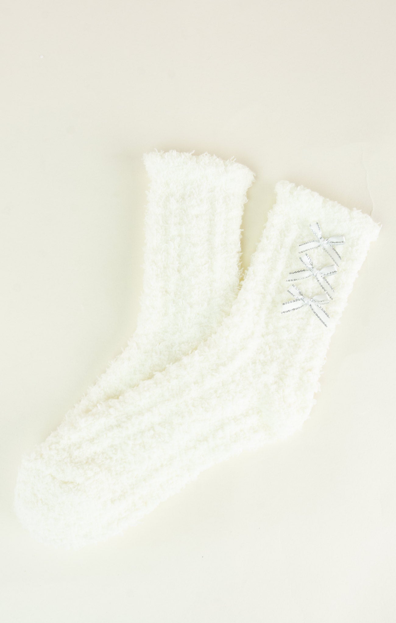 Close-up of a white textured fabric with embroidered details on a beige background