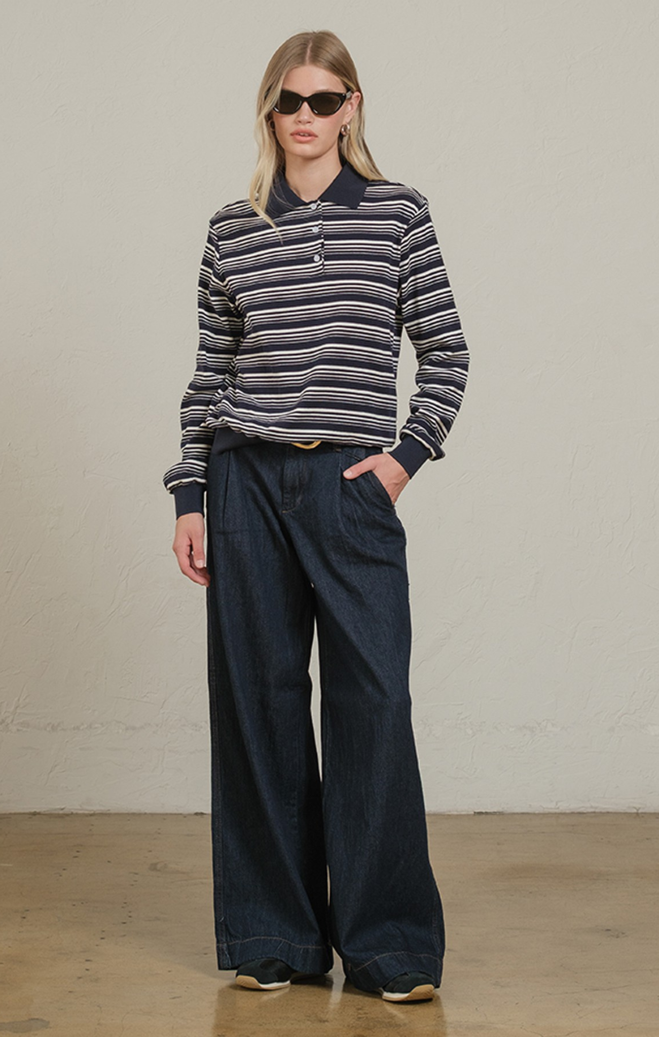 Woman wearing a striped sweater and wide-leg pants against a plain background