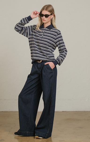 Person wearing a striped sweater and wide-leg jeans against a plain background