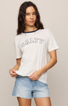 Woman wearing a white t-shirt with 'SALTY' text and denim shorts on a beige background