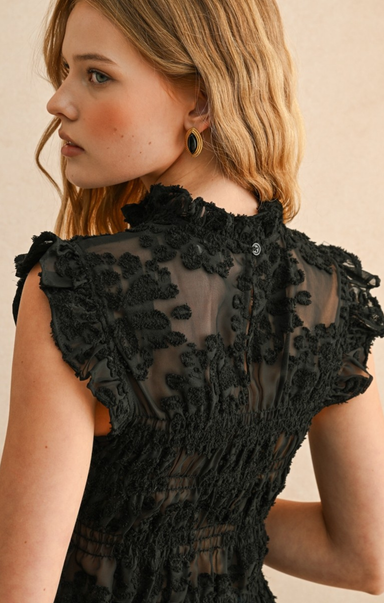 Woman wearing a black lace dress with a neutral background