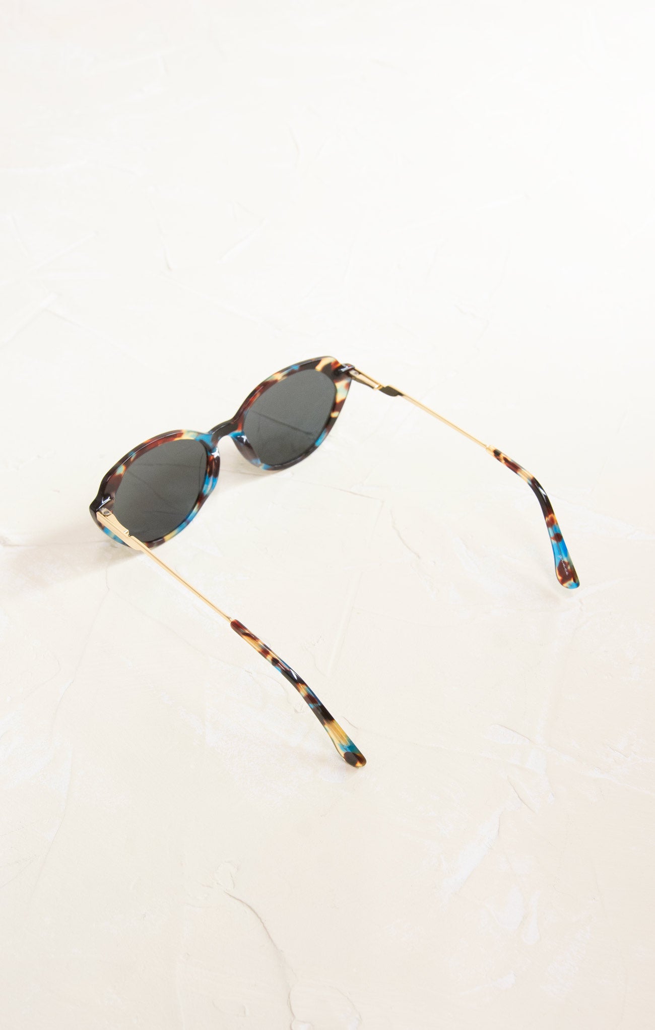 Sunglasses with tortoiseshell frame and dark lenses on a white background