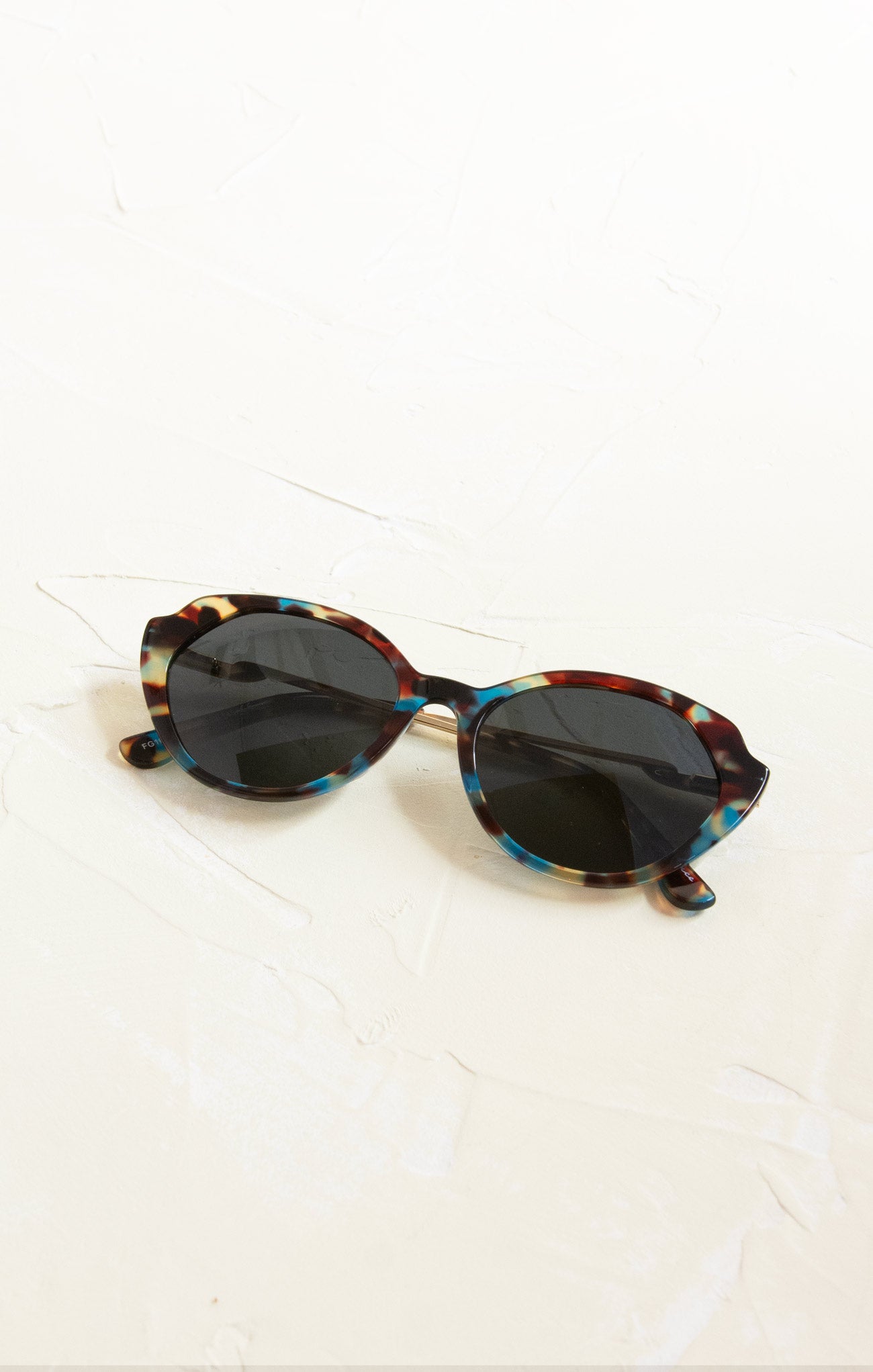 Sunglasses with tortoiseshell frame and dark lenses on a white background