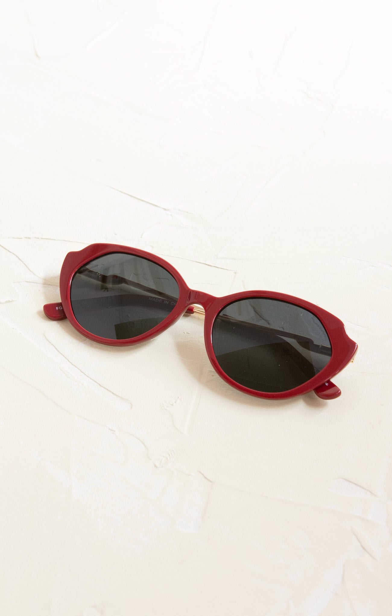 Red sunglasses with dark lenses on a white surface