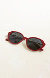 Red sunglasses with dark lenses on a white surface