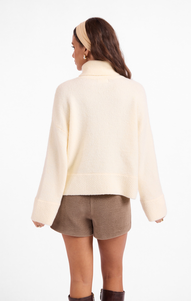 Woman wearing a light-colored jacket and shorts on a white background