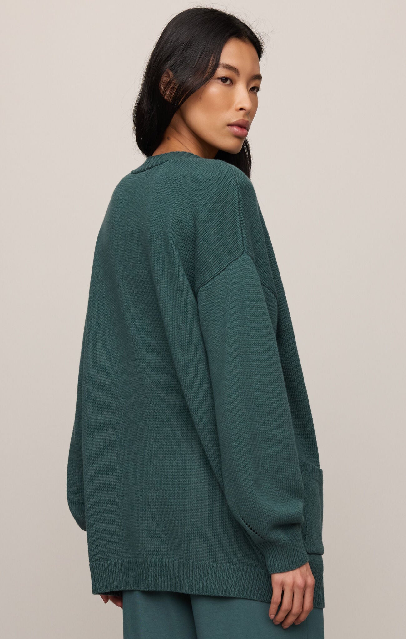 Woman wearing a teal sweater against a plain background