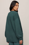 Woman wearing a teal sweater against a plain background