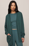 Woman wearing a green outfit with a matching cardigan on a beige background