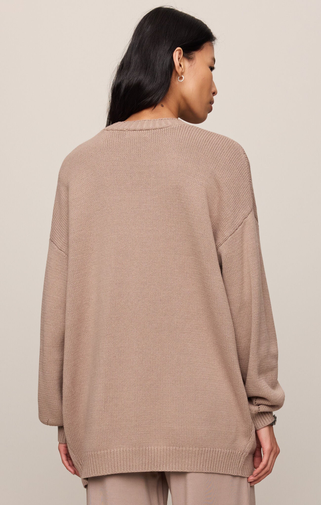 Person wearing a beige sweater against a plain background