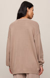 Person wearing a beige sweater against a plain background