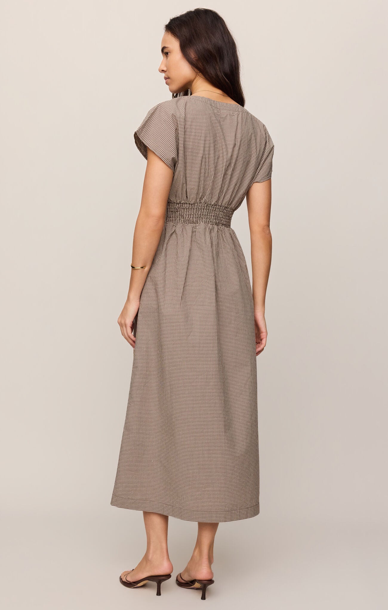 Woman wearing a long brown dress on a plain background