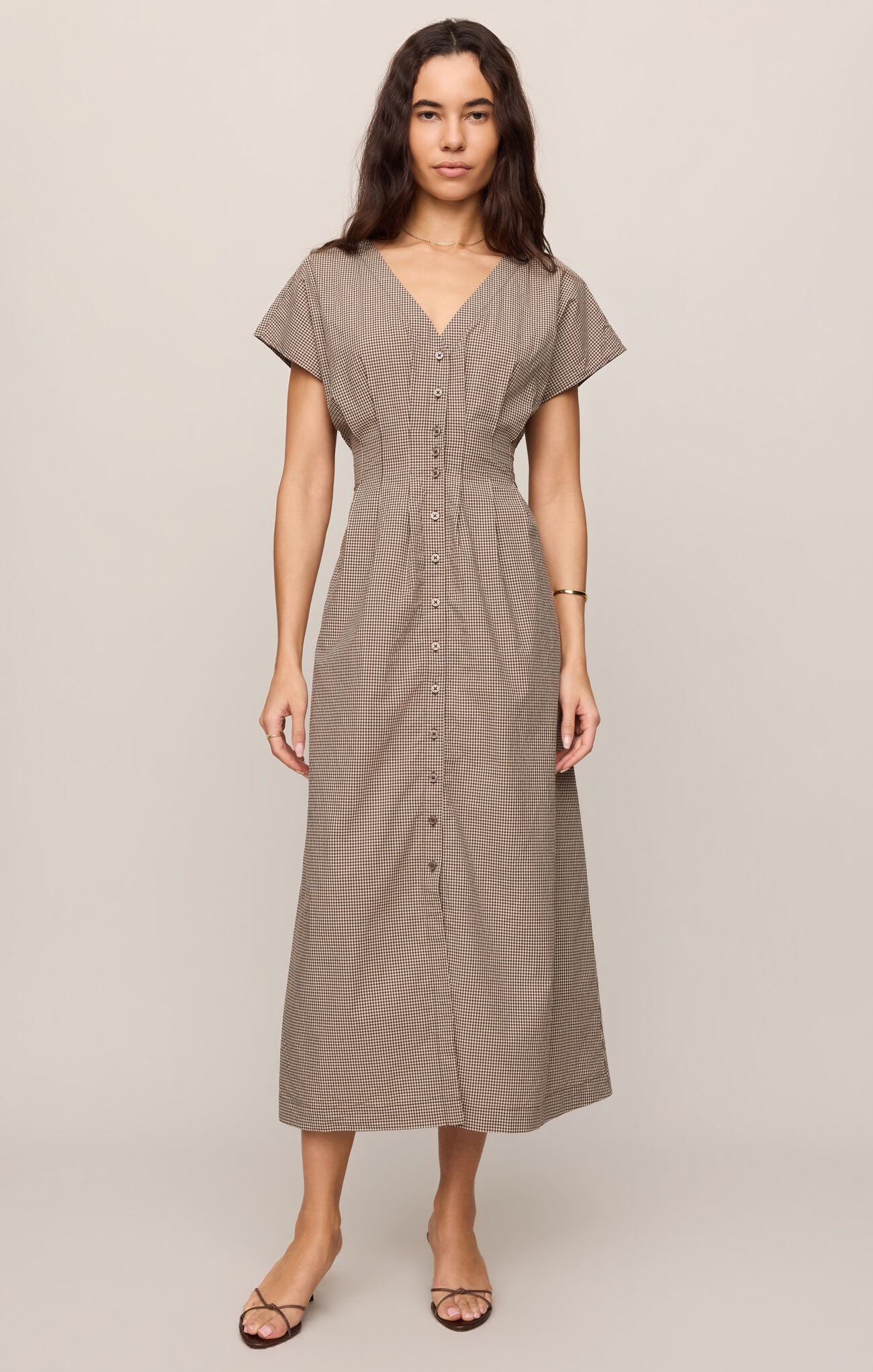 Woman wearing a brown dress against a plain background