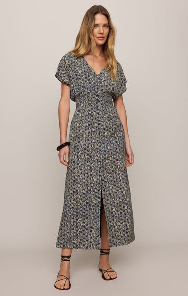 Woman wearing a gray patterned dress on a plain background