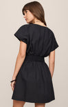 Woman wearing a black dress against a beige background