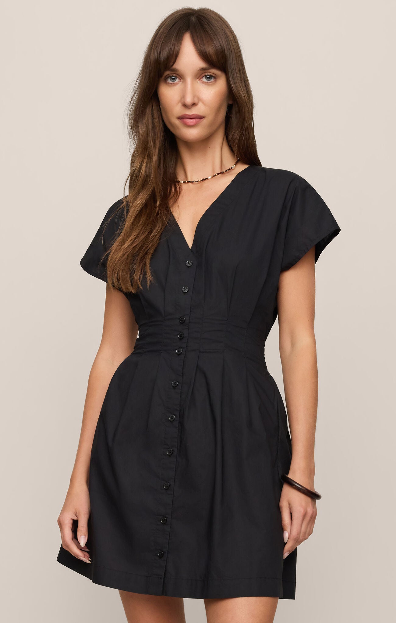 Woman wearing a black dress against a beige background