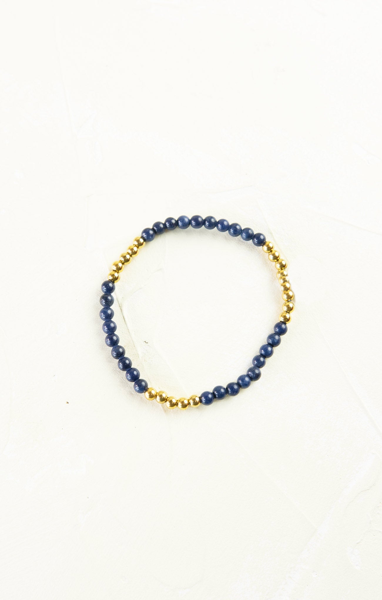 Bracelet with blue beads and gold accents on a white background