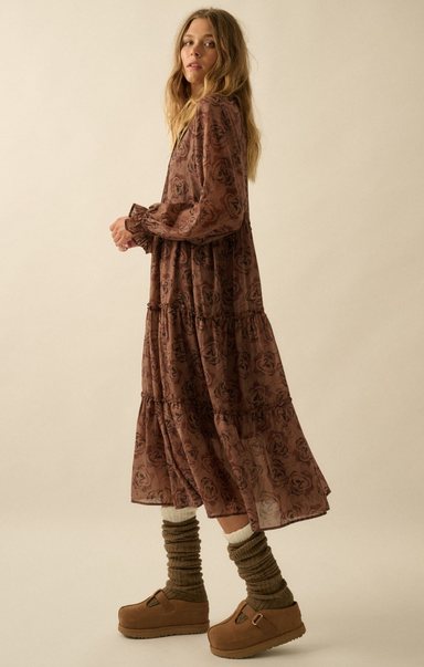 Woman wearing a long brown patterned dress with brown shoes and socks on a beige background