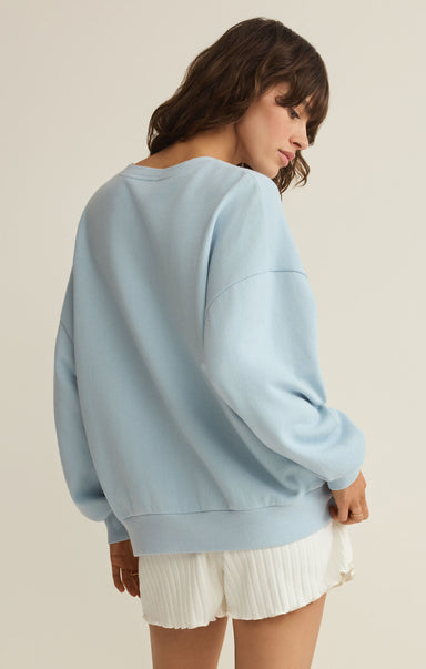 Woman wearing a light blue sweatshirt and white shorts on a beige background