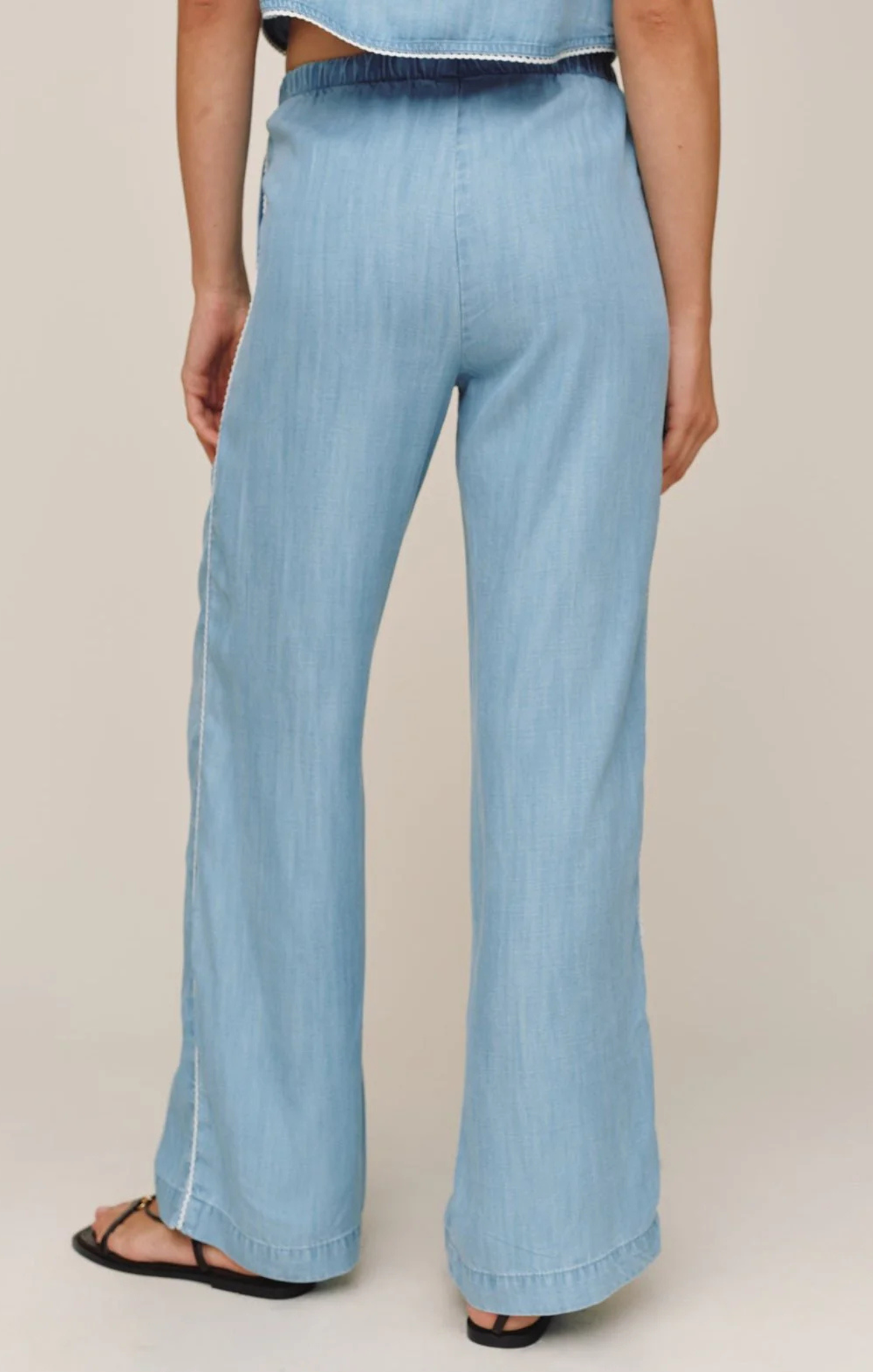 Light blue denim pants worn by a person on a beige background