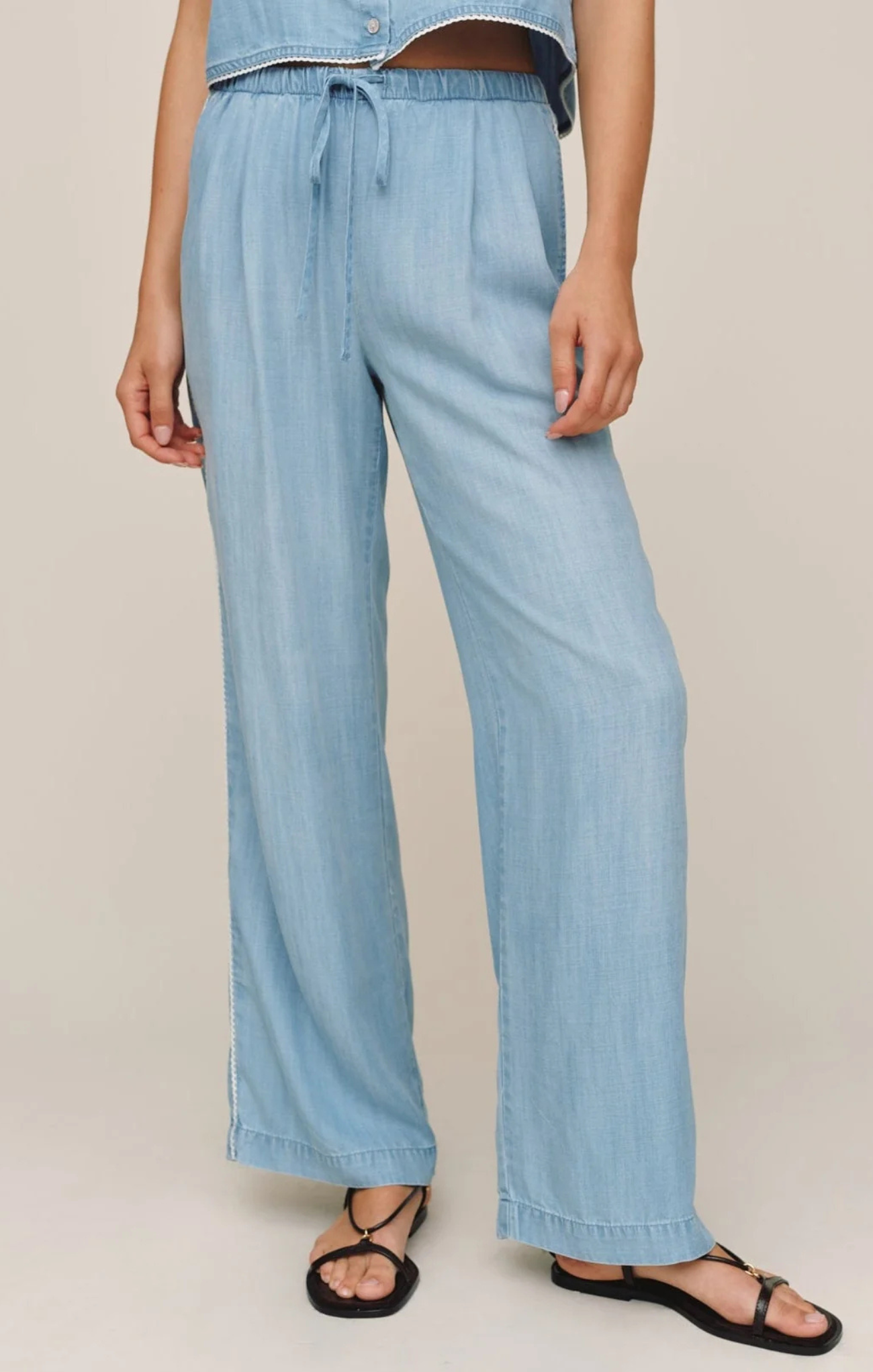 Light blue denim pants worn by a person on a beige background
