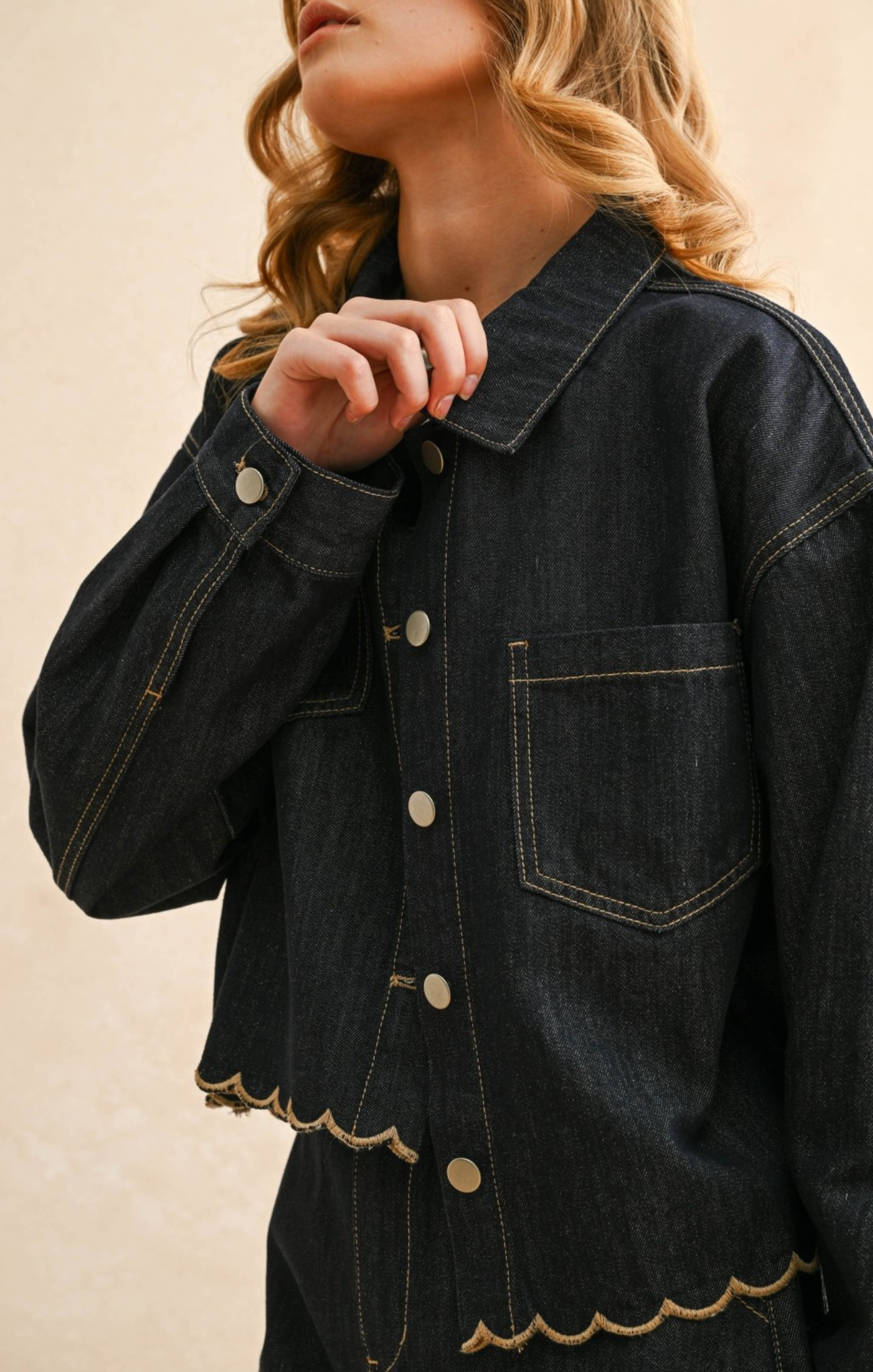 Denim jacket with scalloped hem on a beige background